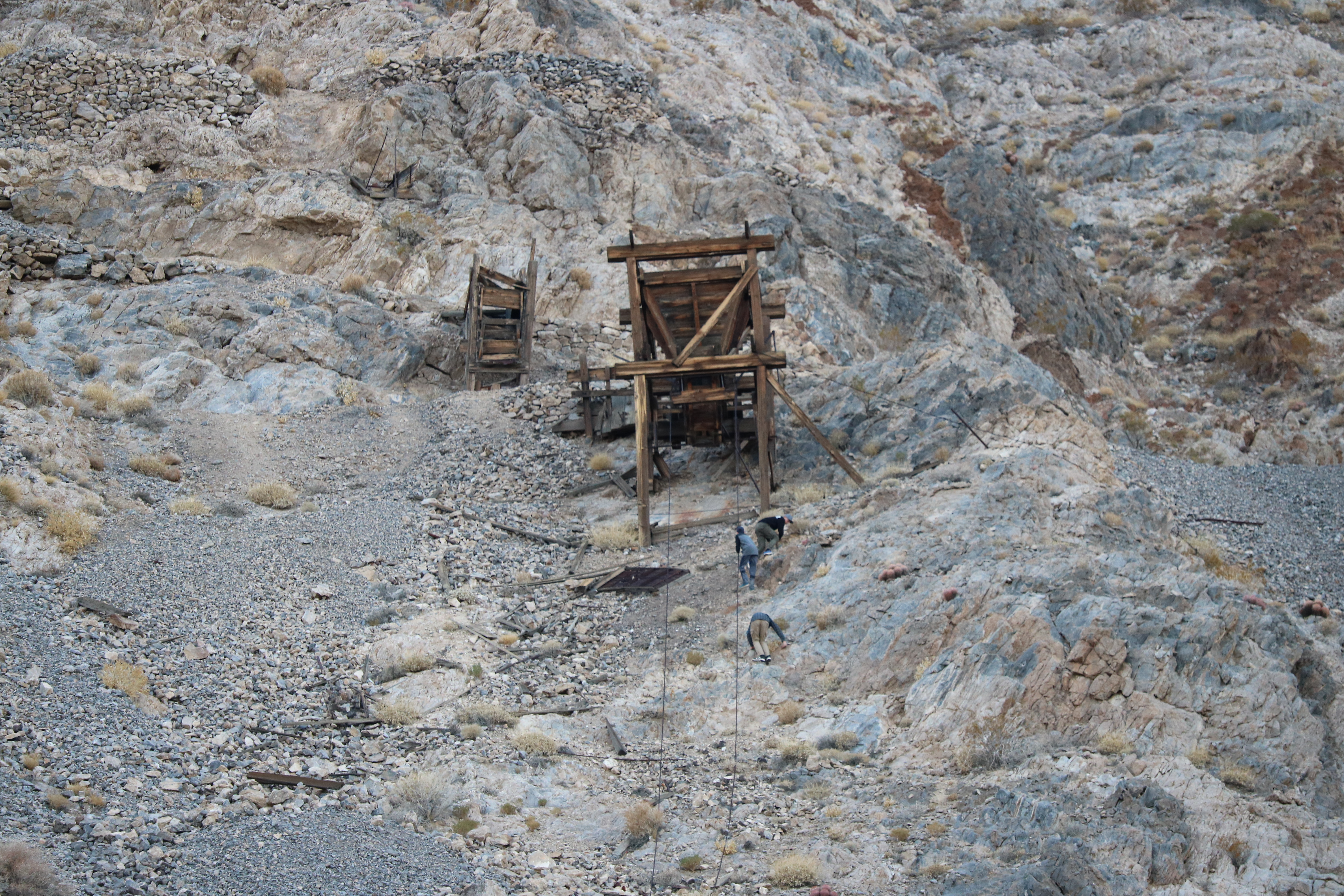 Boys scrambling up a steep hill to reach a wooden structure.