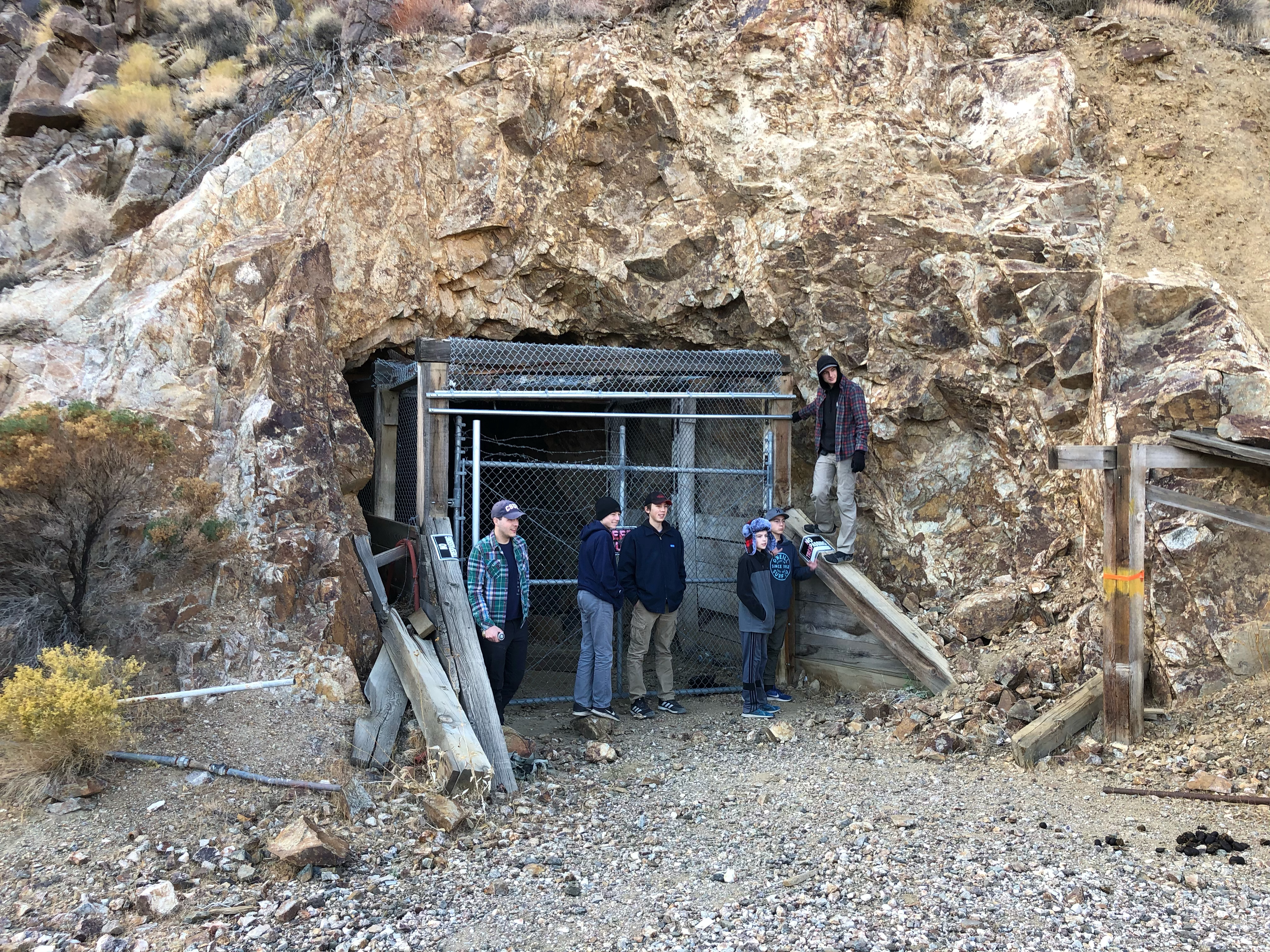 Boys posing in front of a fenced off mine entrance.