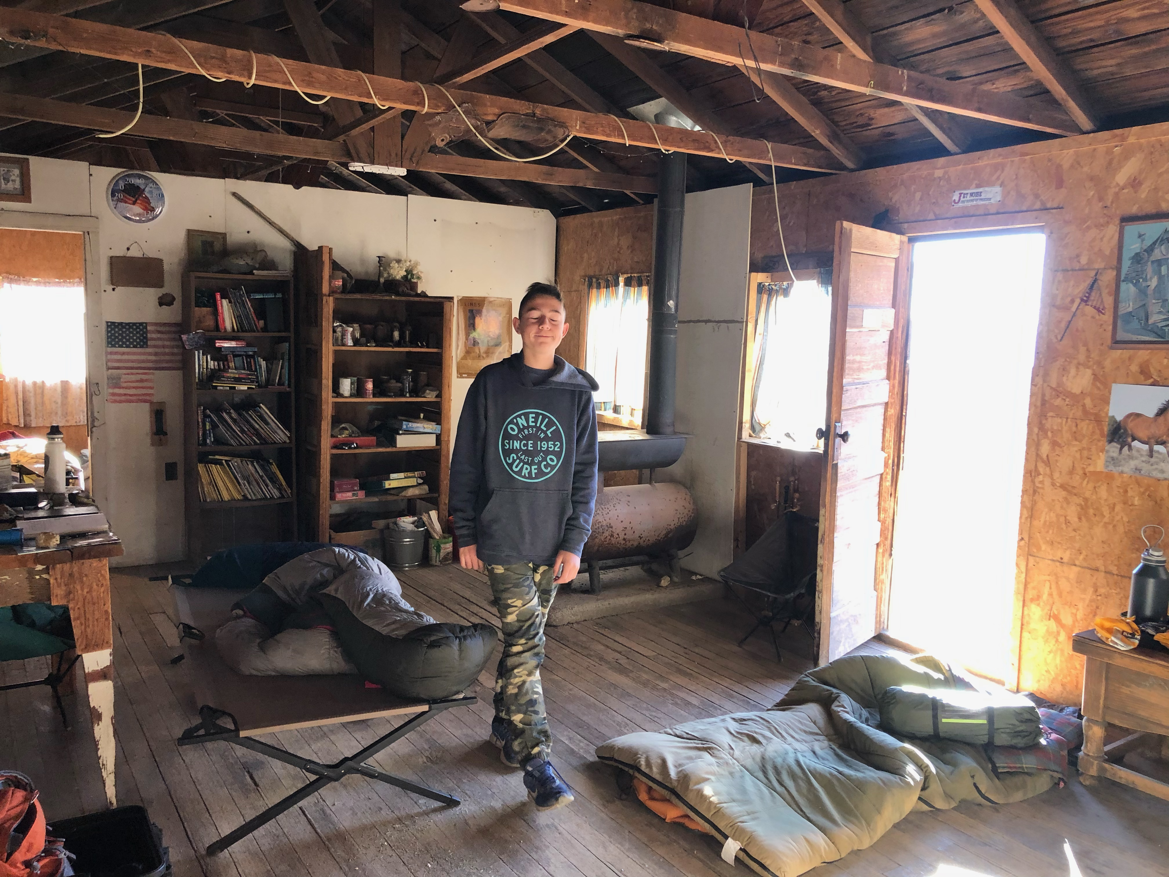 A sleepy boy standing in a cabin living room.