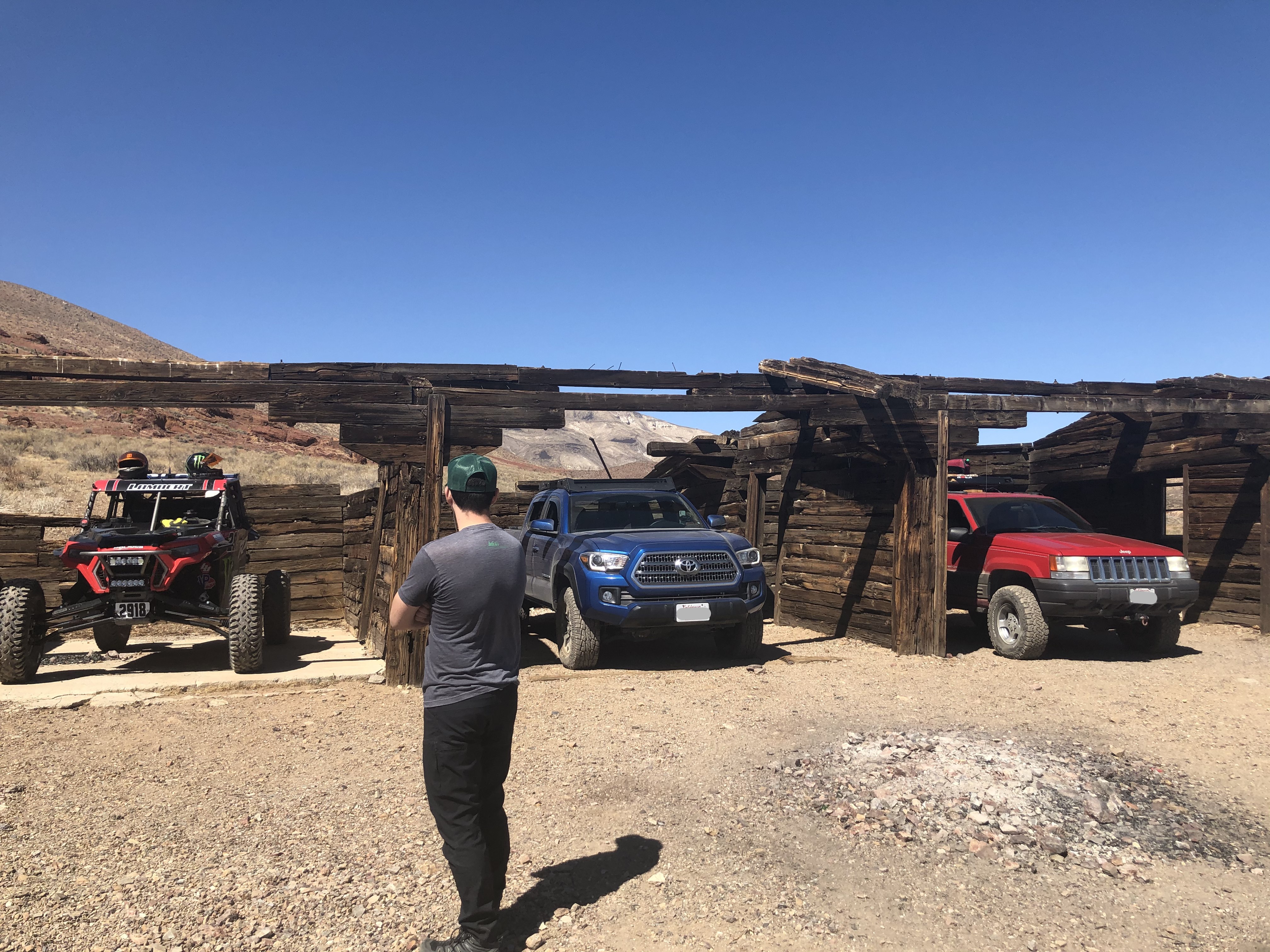 Three vehicles in a wooden stable with a man standing in front.
